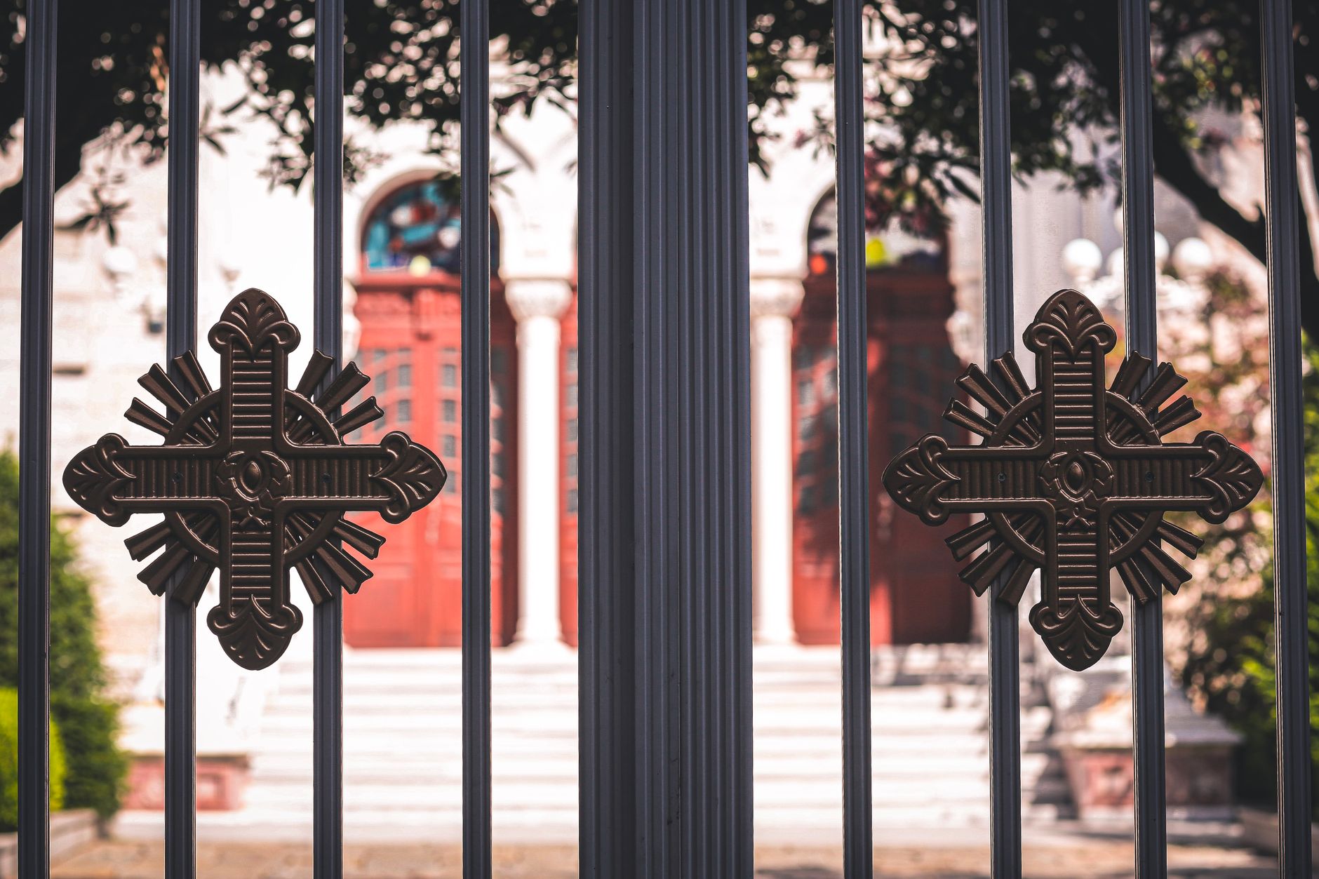 Close-up of a church entrance featuring ornamental metal gates with decorative crosses in Pearland, TX